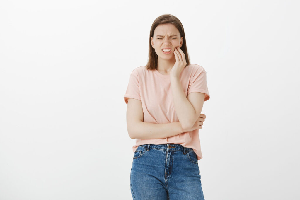 bothered cute woman grimacing from pain touching cheek complaining toothache need dentist